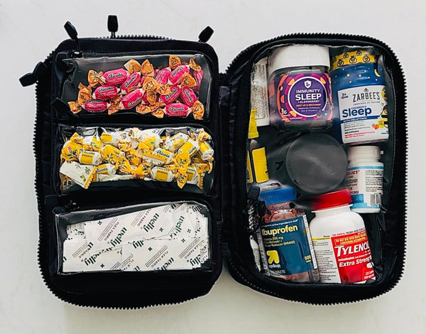 Open first aid kit with medications and snacks on a white background