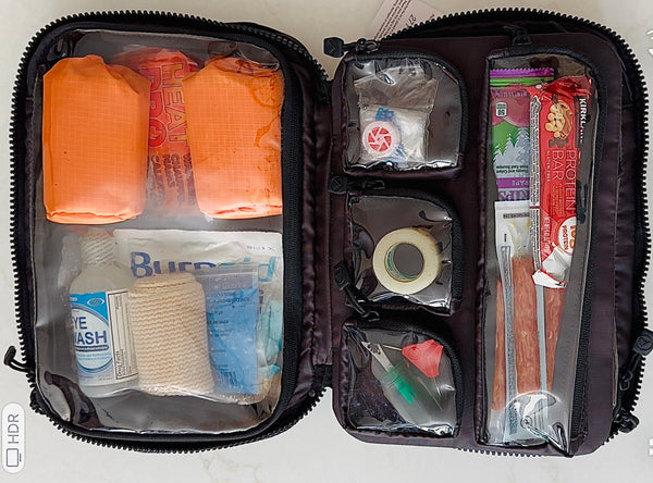 Open first aid kit with various supplies on a white background