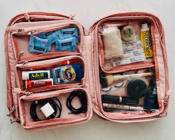 Pink travel organizer with toiletries and makeup on a light background